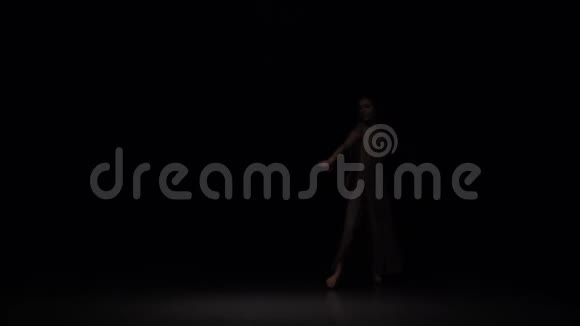 迷人的表演者在黑暗的背景下在暮色中轻舞慢动作视频的预览图