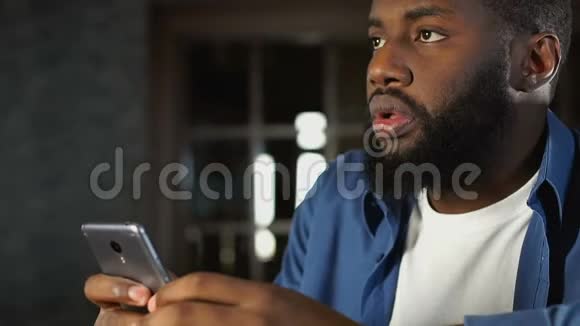 黑人男子在移动应用程序中查看在线投注庆祝运动队的胜利视频的预览图
