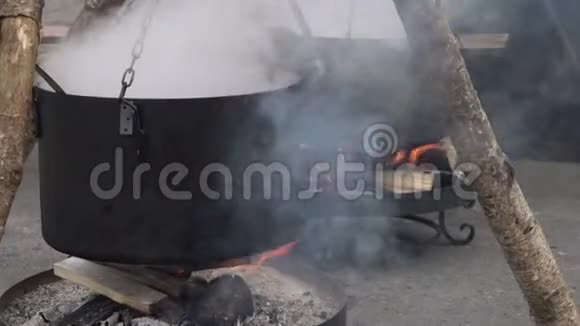 在城市集市上用热的黑烟壶烧开水准备汤或茶在营地的大锅下烧柴火视频的预览图