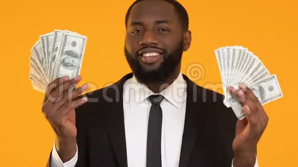 穿着西装的自信的黑人展示了美元并把空气吻送到相机上视频的预览图