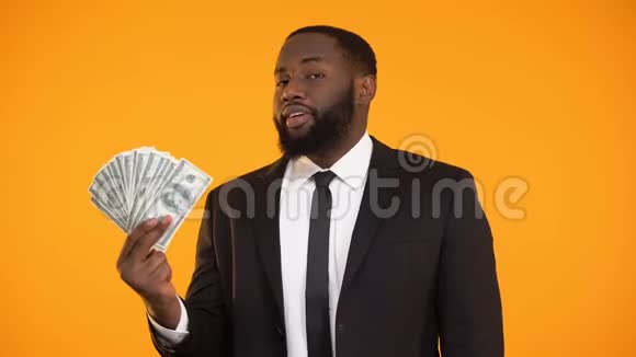 满意的黑人商人展示了美元现金和竖起大拇指的手势收入视频的预览图
