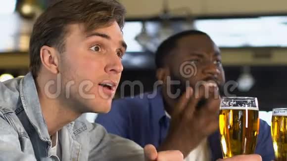 情绪化的男人在酒吧里碰啤酒杯看体育比赛冠军赛视频的预览图