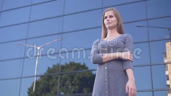 可爱的年轻女孩在城市环境中行走一个穿灰色裙子的快乐女孩在一栋玻璃建筑附近视频的预览图