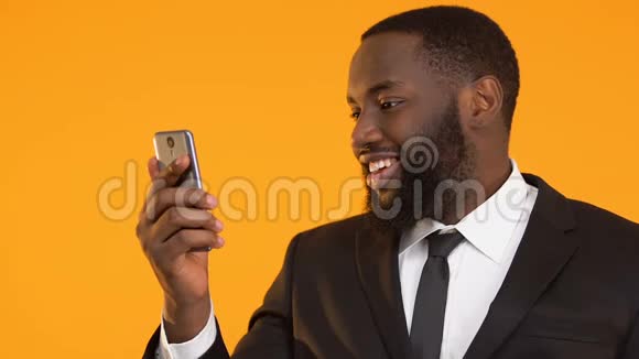快乐的黑人穿着西装拿着智能手机竖起大拇指用现金回馈应用程序视频的预览图