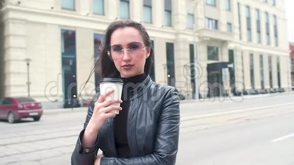穿夹克的女孩背景是街道摘下太阳镜喝咖啡视频的预览图