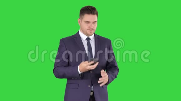 体贴的年轻商人穿着西装打着领带在绿色屏幕上快速打了几个电话Chroma键视频的预览图