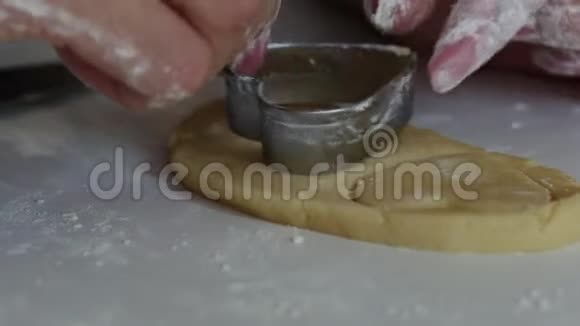 一个女人用刀子从桌子表面取出卷制面团中的饼干特写镜头视频的预览图