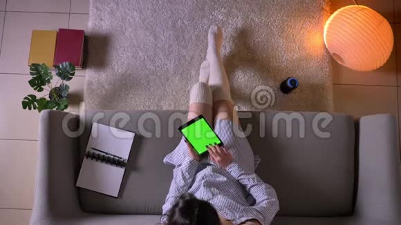 一位年轻有魅力的女性博客写手在平板电脑上打字坐在沙发上用绿色的彩色屏幕特写镜头视频的预览图