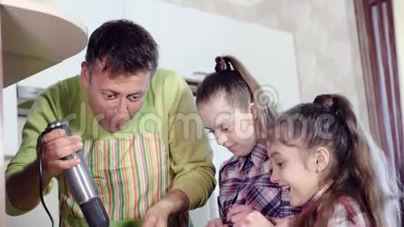 家庭的快乐父亲和女儿一起用厨房搅拌机准备晚餐视频的预览图
