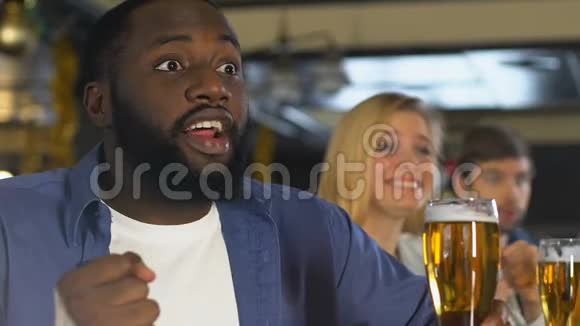 带着啤酒的年轻人在酒吧里看赛马为胜利欢呼视频的预览图