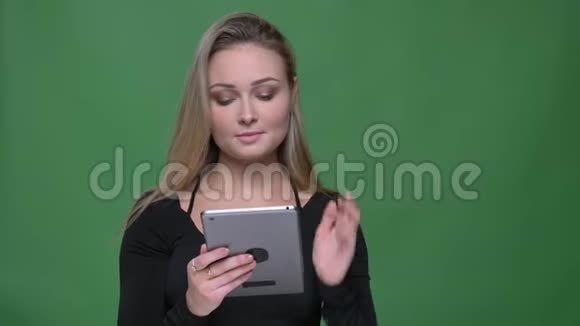 女商人穿着黑色上衣在绿色的背景下专注认真地看着平板电脑视频的预览图