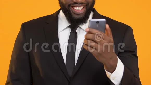 穿西装的快乐非裔美国男性手持智能手机显示是的手势彩票视频的预览图