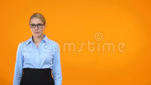 戴着眼镜的漂亮年轻女子在橙色背景上竖起大拇指视频的预览图
