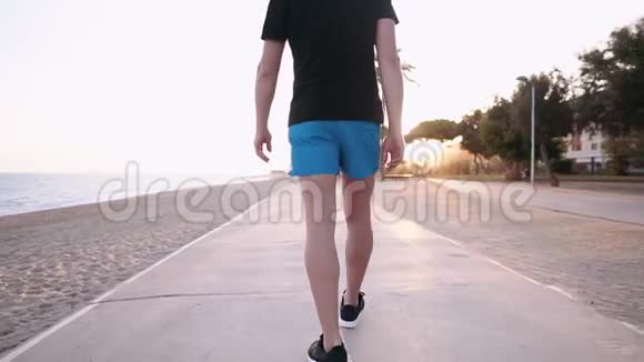 日落时分成年男子沿着海堤走过小路后景视频的预览图