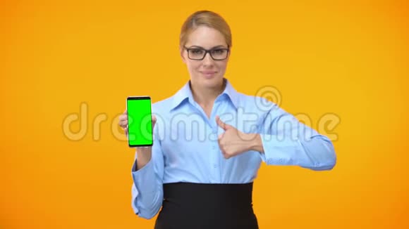 公司女员工竖起大拇指举着绿色屏幕的智能手机视频的预览图