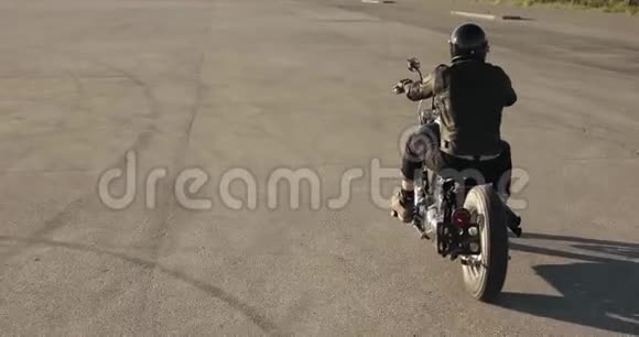 男子自行车骑摩托车在城市的道路上日落后景视频的预览图