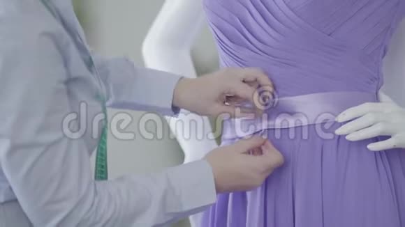 女人纠正优雅的紫色连衣裙挂在房间里的人体模型上裁缝在车间工作缝纫视频的预览图