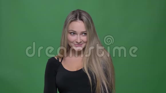 年轻女商人穿着黑色上衣谦虚地微笑着进入镜头在绿色背景下快乐的肖像视频的预览图