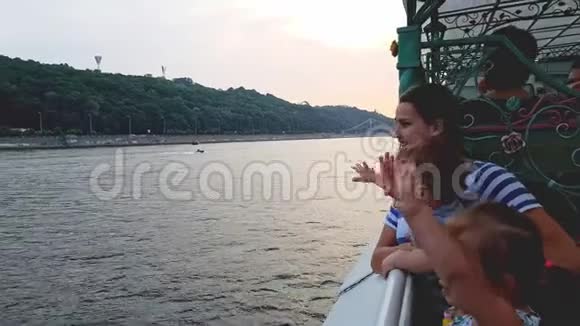 4K母亲带着两个孩子漂浮在一艘小船上坐在第聂伯宽阔的河上望着船上视频的预览图