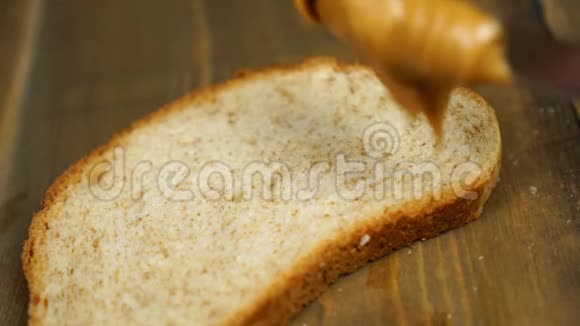人做花生酱三明治男性手在厨房的面包上涂黄油视频的预览图