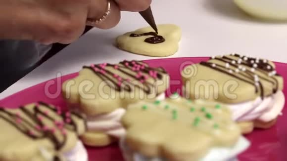 棉花糖三明治的空白放在盘子里可见装饰点缀在巧克力上女人用巧克力装饰饼干关闭视频的预览图