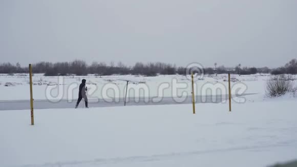 白天有人在森林附近的冬天沿着河边的雪夏海滩滑雪体育与健康视频的预览图