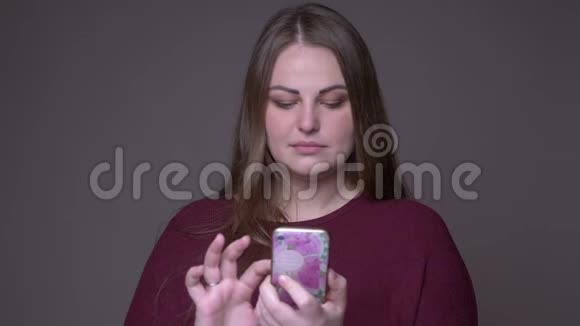 年轻超重的白种人女性在手机上浏览社交媒体的特写镜头背景与外界隔绝视频的预览图