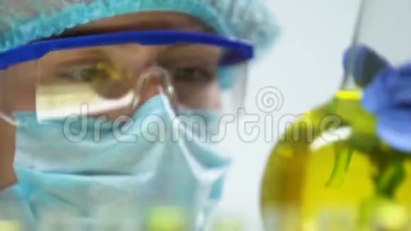 研究人员用绿色植物标记瓶保存在黄色液体中特写视频的预览图