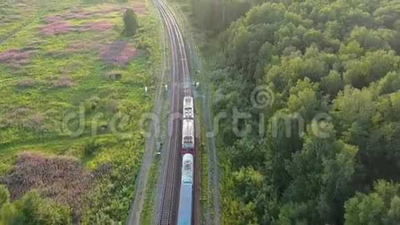 火车驶进远处的俄罗斯森林里日落时的空中景色无人驾驶飞机的4k段录像视频的预览图