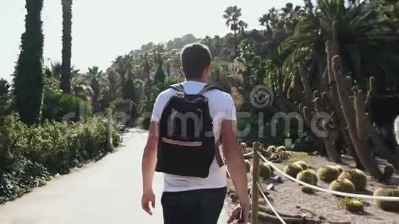 男游客在阳光明媚的巴塞罗那神奇的仙人掌公园散步视频的预览图