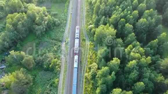 日落时在夏季松林上行驶的郊区火车通勤铁路的鸟瞰图无人驾驶飞机的4k段录像视频的预览图