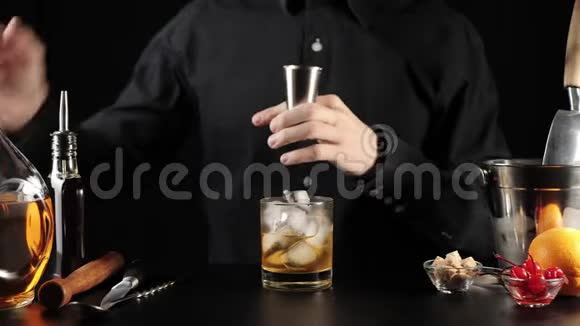 老式鸡尾酒酒保拿着一个跳汰机从一个圆形瓶子里倒波旁威士忌然后倒第二部分波旁威士忌视频的预览图