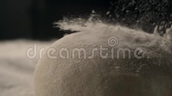 在厨房的桌子上用面粉做酵母面团用暗键烹饪食物慢动作烹饪视频的预览图