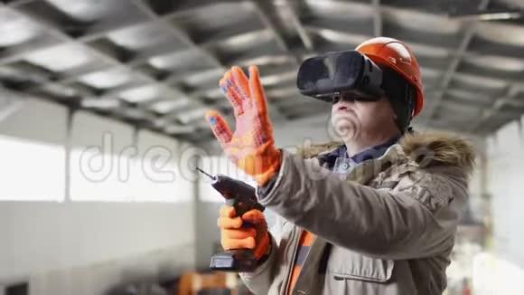 戴着安全帽穿着工作服的人正站在机库中间用虚拟现实眼镜在机库上打洞视频的预览图
