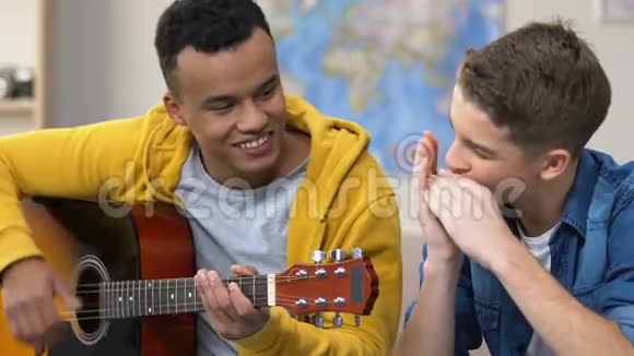 两个青少年朋友喜欢一起弹吉他和口琴爱好音乐视频的预览图
