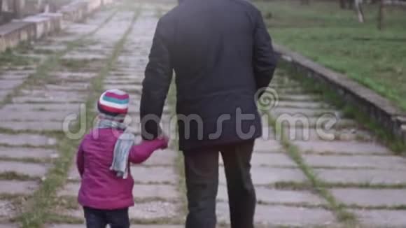 后景孙女和爷爷牵着手在城市公园散步视频的预览图