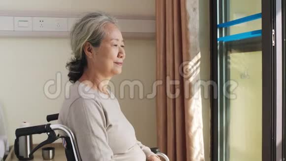 坐在靠窗的轮椅上的亚洲老女人视频的预览图