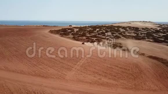 电影镜头汽车穿越红色沙漠土地在空中投掷沙子和泥土被海洋包围视频的预览图