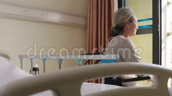 坐在靠窗的轮椅上的亚洲老女人视频的预览图