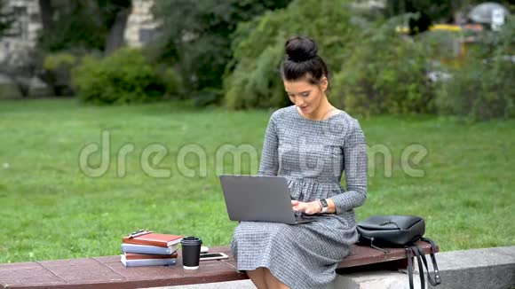 女学生正在公园的现代笔记本电脑上打字视频的预览图
