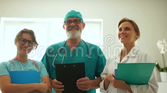医生和两名护士正在镜头前摆姿势医生笑着站在窗前抱着视频的预览图