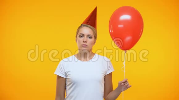 悲伤的成年女人拿着气球吹着噪音制造者生日聚会上心情不好视频的预览图