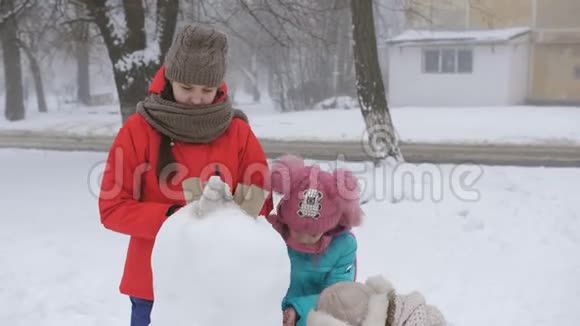 妈妈和两个女儿在冬天装饰鹅卵石一起堆雪人视频的预览图