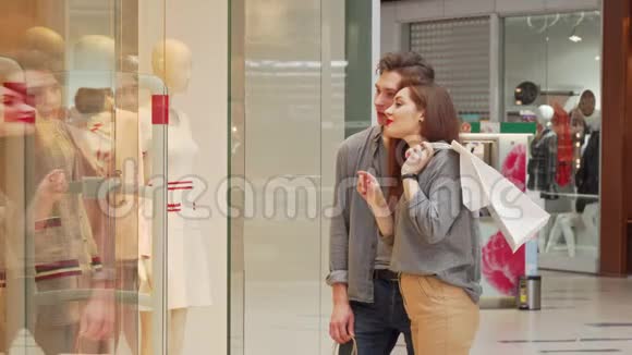 快乐的年轻夫妇一起购物在商店里检查衣服视频的预览图