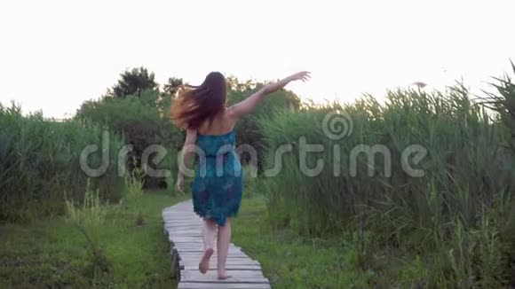 迷人的女孩赤脚在户外的木桥上奔跑在绿草如茵的草地上享受大自然视频的预览图