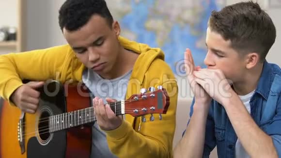 两个弹吉他和口琴的青少年音乐爱好业余音乐家视频的预览图