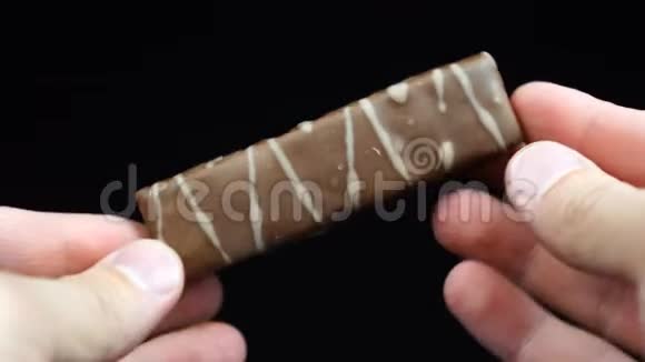 黑色背景下男人手中的巧克力棒视频的预览图