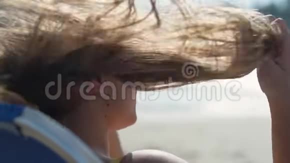 迷人的年轻女孩在风中挺直头发享受海边的美妙天气慢动作关闭视频的预览图