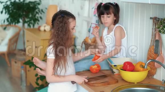 女孩在厨房里切胡椒她姐姐坐在桌子上吃面包慢动作视频的预览图