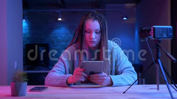 年轻有魅力的女性博客写手在平板电脑上发短信笑着欢快地现场直播视频的预览图